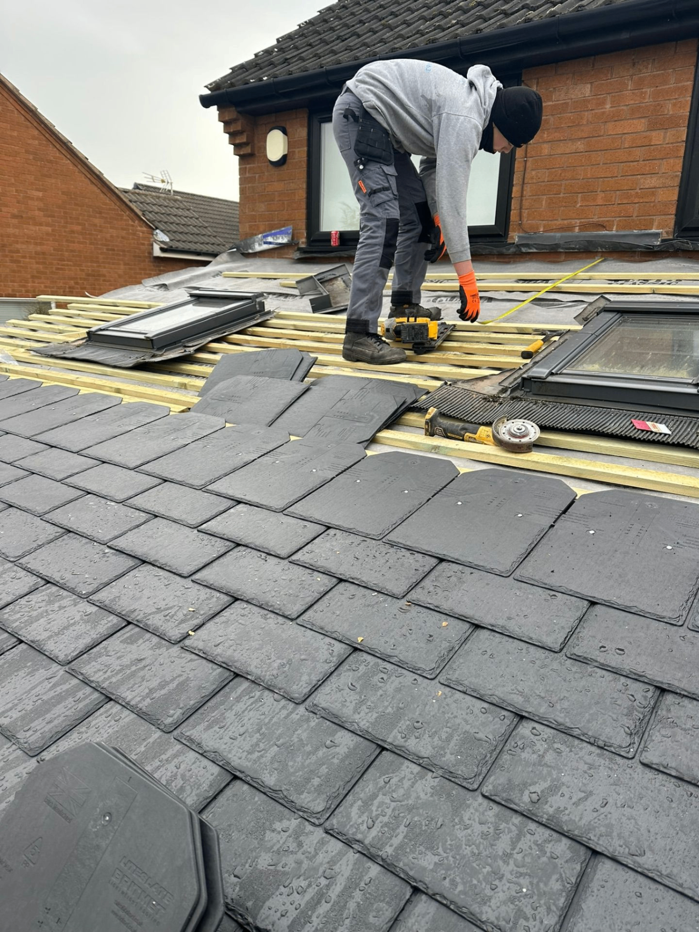 Sherwood roofer fitting new slate tiles on battens and breathable membrane during a re-roof